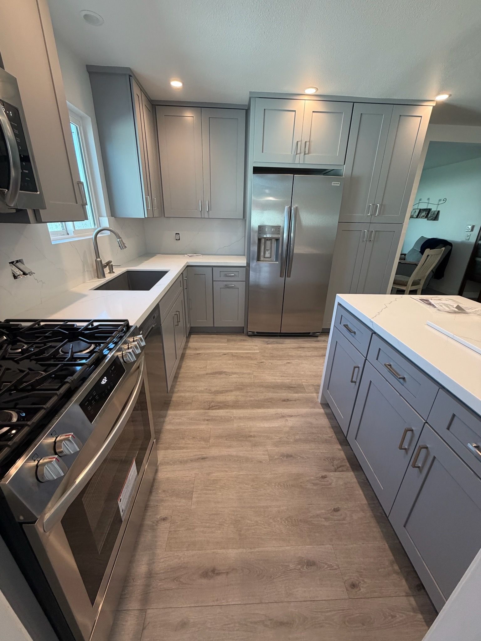 A Radach Construction kitchen: stainless gas range and undermount sink set into quartz counters beneath grey shaker cabinetry