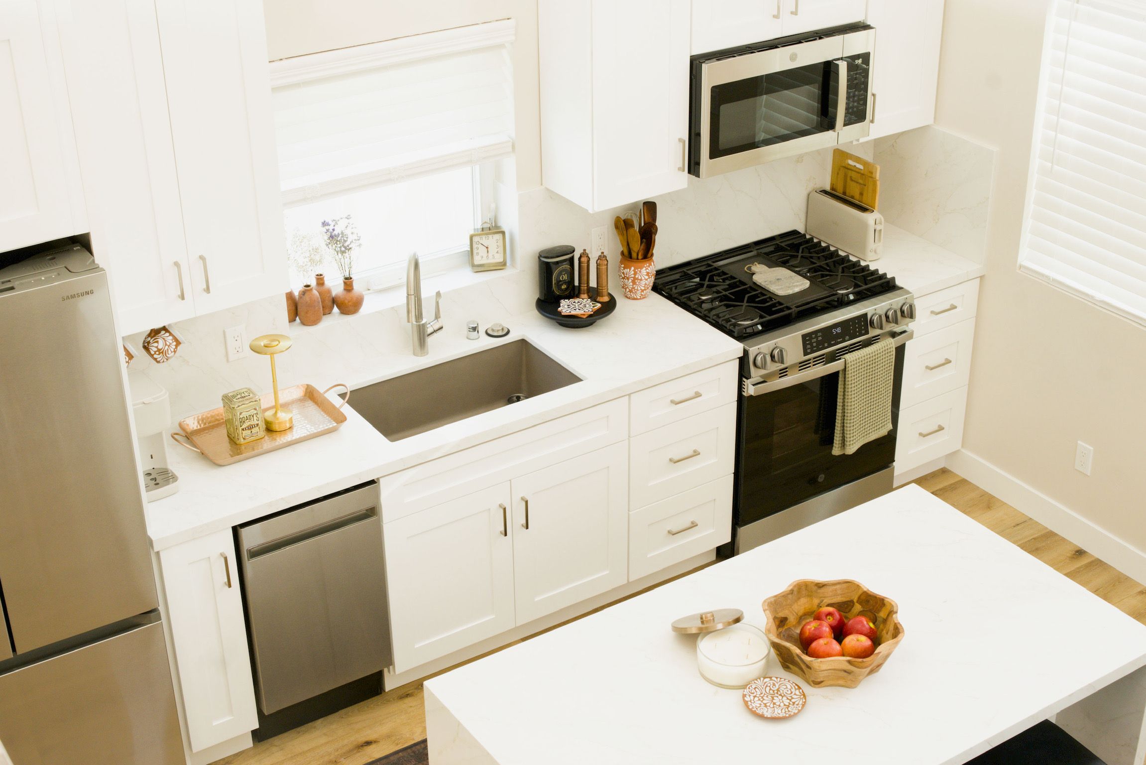 Remodelled kitchen in white shaker cabinetry with quartz counters, a marble-look slab backsplash and a seated island